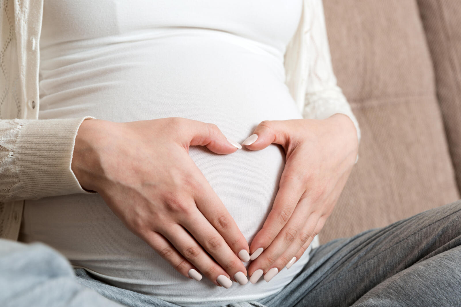 Young pregnant woman holds wooden heart. Love concept.